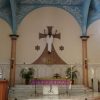 The sanctuary of Carmelite Church is mainly white and beige on walls and pillars, while the ceiling has a blue and white cloud-like pattern. The center of the wall behind the altar depicts Jesus in his risen form; both hands are raised and wearing white. The sanctuary is one step above the main floor, and behind the altar are three steps to where the priest's chair and the tabernacle are situated. The tabernacle is a metallic box on the wall below the risen Jesus. The altar is draped with a purple cloth and has chi-rho christogram on the front surface of its stand. A wooden lectern is also on the right of the sanctuary (left as seen from the nave) just outside the first elevated step.