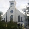 The church building of Christ the King Parish as seen from along Bansalangin St. north of Calumpit St. The frontage is mostly white with five half-oblong and one circular glass windows.
