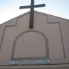 Upper part of the structure of Parish of the Holy Cross. It is colored pink and has cross on top and the words HOLY CROSS PARISH in metallic letters.