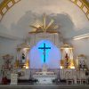 The sanctuary of Immaculate Conception Parish is mostly white with gold tone highlights. Its shape is that of a domed tower with white altarpiece in front of the wall. A goldtone half-disc sun-like decoration with seven rays radiating upward and sideways is on the top center of the altarpiece or reredos. Below the sun-like decoration is a crucifix with blue light coming from its back. The tabernacle is below the crucifix: a compartment with a dome top and two goldtone statues of angels on its left and right. On left and right of the crucifix (as seen from the nave) are smaller compartments containing the statues of Joseph and Mary respectively. Mary is in white and blue and has a crown made of stars. Joseph is in yellow and green, holds a staff, and has goldtone halo radiating from the back of his head. The altar is in front of the tabernacle and is covered with a white cloth. On the left of the altar is a white lectern with goldtone decorations of lion, ox, eagle, and man with wings. A microphone stand, a smaller podium, and three white chairs are seen on the right of the altar.