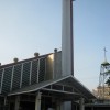 The external structure of Our Lady of La Paz church. It has triangular roof and triangular shade at the entrance. It's cross extends to height that seems like double the height of the main structure. A separate structure contains the bells.