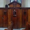 This small brown chamber is one of the several confessionals of Our Lady of Pillar Church. It has three doors: the one at the center is for the confessor, and the ones of the sides are for the penitents. The section for the confessor has a pentagonal decorative roof that looks like a mitre and decorated with two keys forming an X in front. The number 4 is also attached in front of the confessor's door.