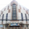 The frontage of Our Lady of Perpetual Help Parish in Cubao, Quezon City. The color is predominantly white with some pink sections. The roof is triangular with a cross on top. There are small glass windows, and the center section underneath the cross is mostly pink with large glass panes showing portraits of Mary carrying Jesus as well as an angel behind the glass. The churchyard is surrounded with white steel barriers attached to pink concrete pillars, with white steel gate at the center. The main door is brown with gold-colored decorated knobs at the center. There is a protruding roof between the main door and the gate, on which the silver-colored letters OUR LADY OF PERPETUAL HELP is embedded.