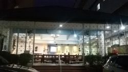 The Our Lady of Mt. Carmel Chapel appears as a small separate building from the hospital. It has a triangular roof and only white railings for a wall. The main entrance in this picture is open; it has a red staircase leading up the chapel. Some of the icons and statues inside are visible from outside.